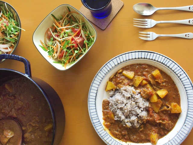 テーブルに並ぶカレーとサラダとカトラリー