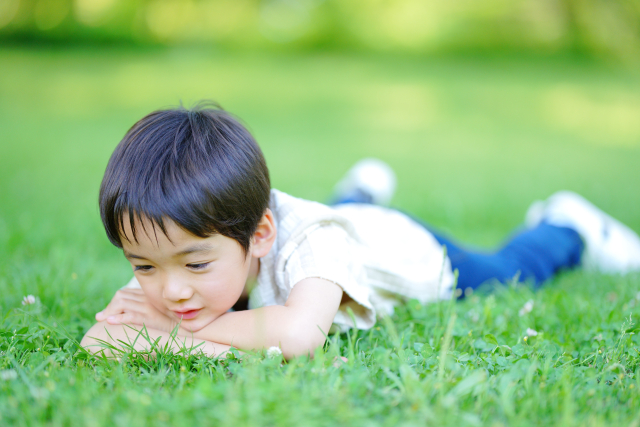 寝転んで芝生を見ている男の子